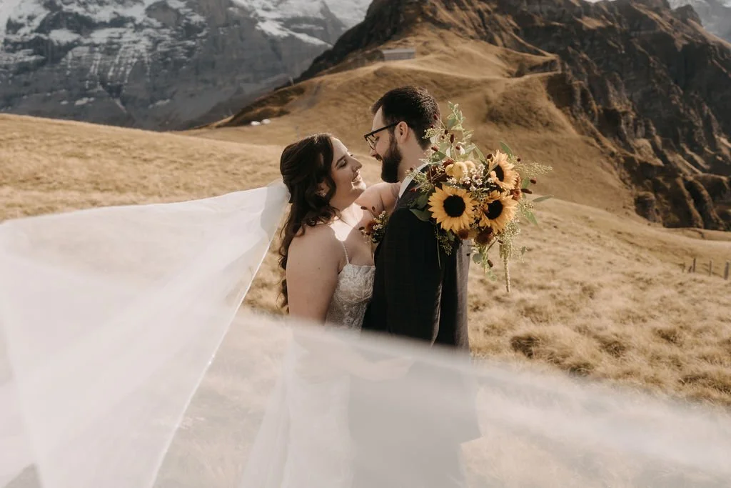 A bride and groom with a sunflower bouquet and a flowing veil, Switzerland elopement