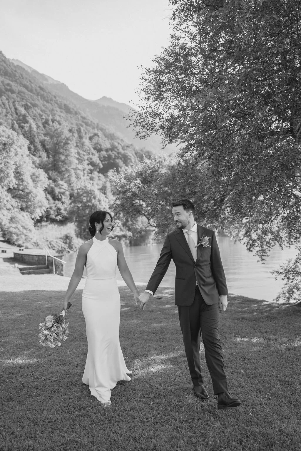 A black and white photo of a couple holding hands by a lake, Switzerland elopement