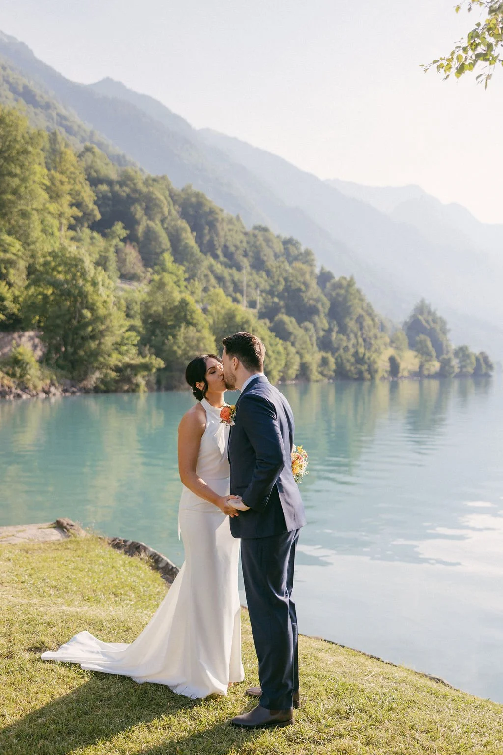 A couple kissing beside a turquoise alpine lake, Switzerland elopement