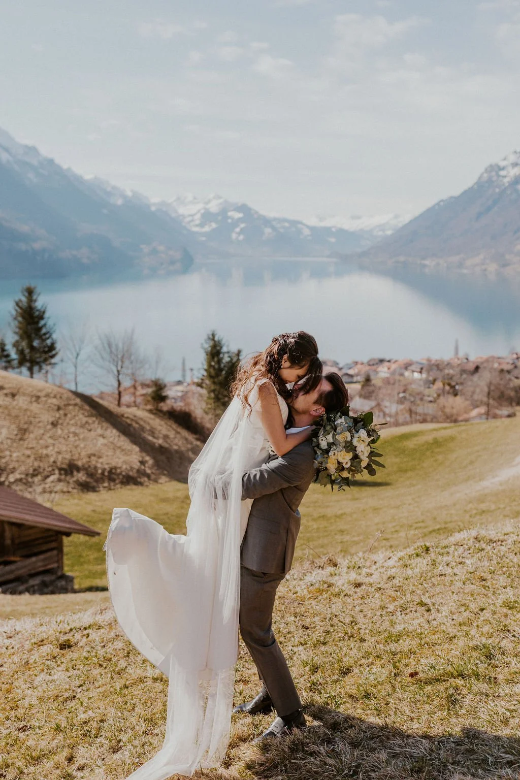 A couple embracing on a hillside above an alpine lake, Switzerland elopement