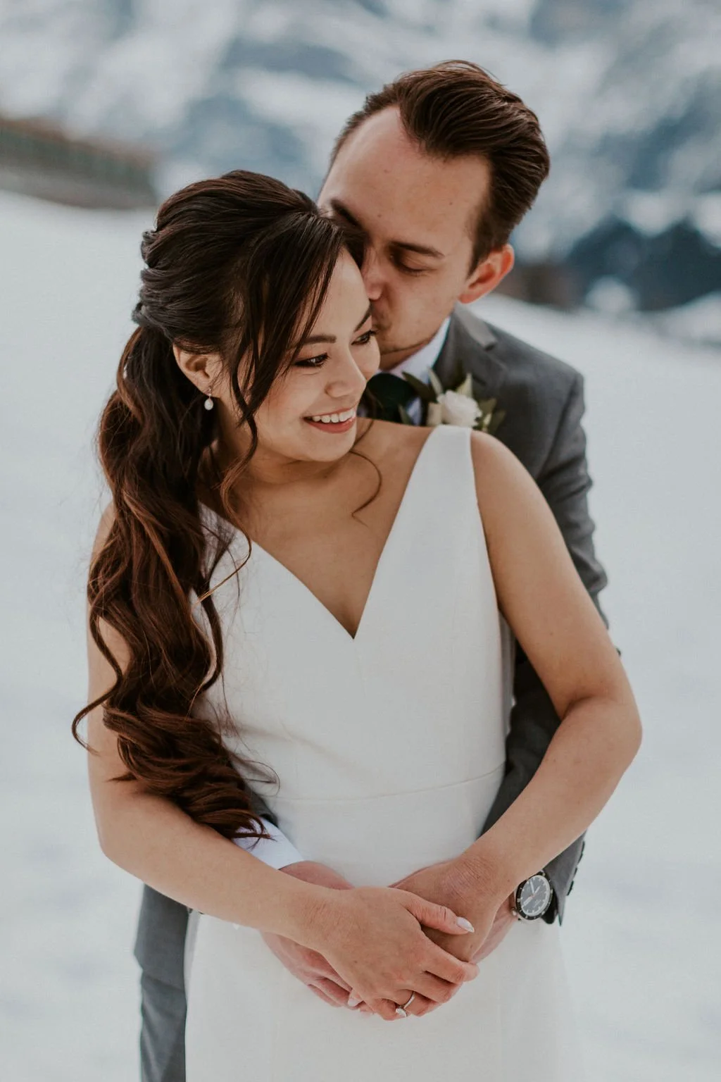 A bride and groom embracing in the snow, Switzerland elopement