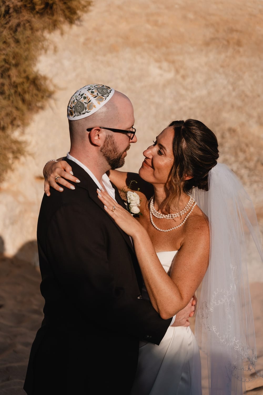 A couple in a close embrace against warm golden rock