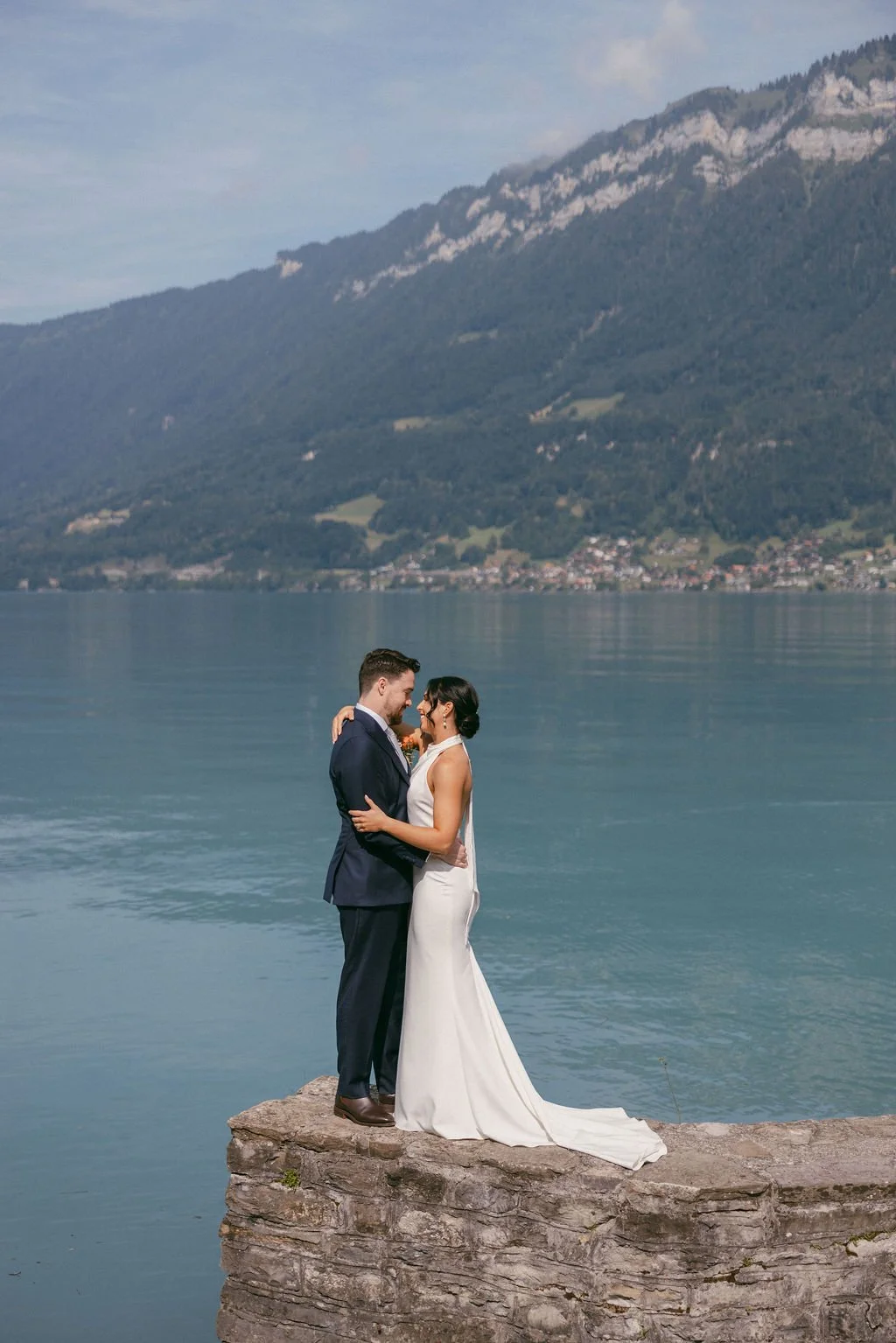 A couple on a stone jetty on a turquoise lake, Switzerland elopement